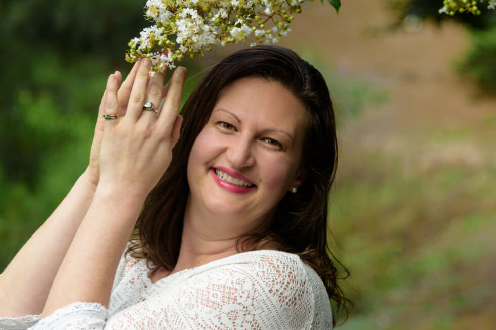 Image of Intuitive Nicole Leffer with hands in prayer under a flowering tree